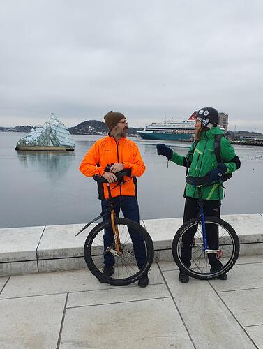 two men with unicycles talking to each other