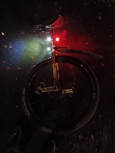 Unicycle resting on icy ground in the dark. The lights illuminate the ice and make it look like water.